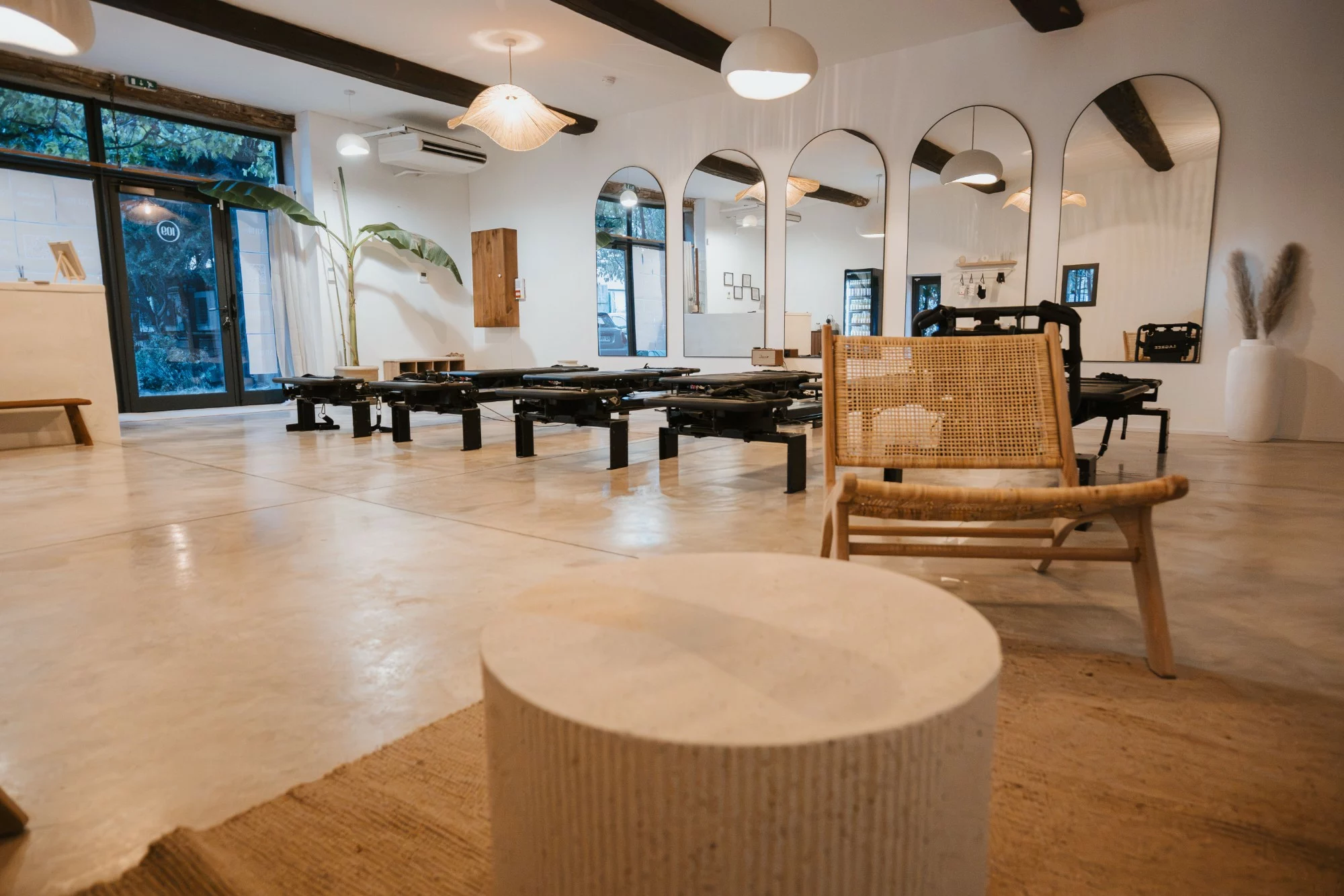 La salle du studio STUDIO.109 à Perpignan : machines Lagree, miroirs en arche et coin d’accueil en rotin
